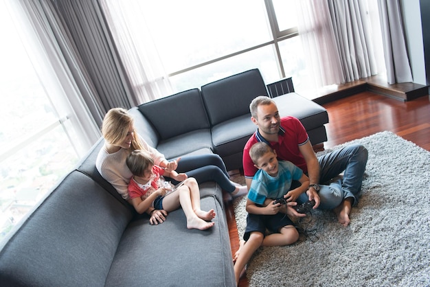 Happy family. Father, mother and children playing a video game Father and son playing video games together on the floor