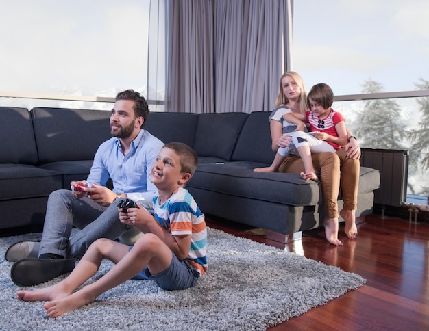 Happy family. Father, mother and children playing a video game Father and son playing video games together on the floor