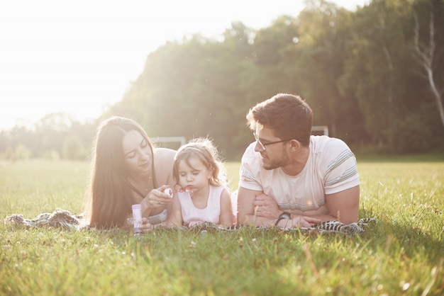 Happy family, father of mother and daughter of baby in the nature at sunset