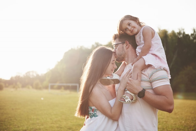 Happy family, father of mother and daughter of baby in the nature at sunset