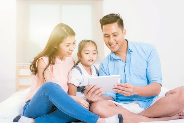 Happy family father, mother and little girl on the bed at home