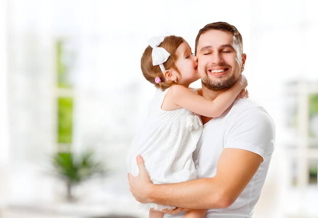 幸せな家族と父の日の子供の娘がお父さんにキスして抱き締める