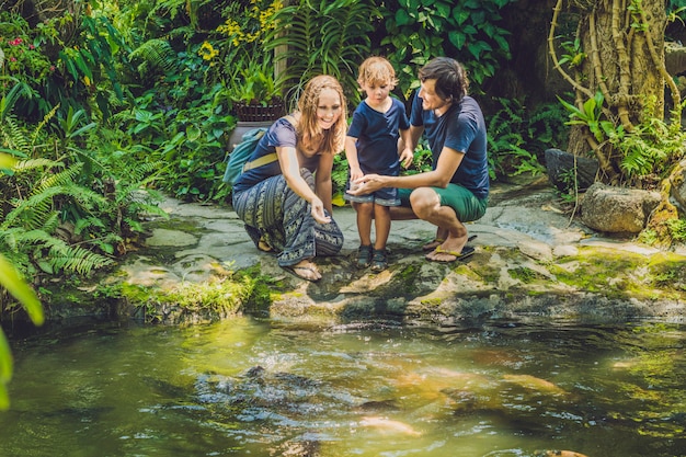 Happy family feeding colorful Catfish in tropical pond