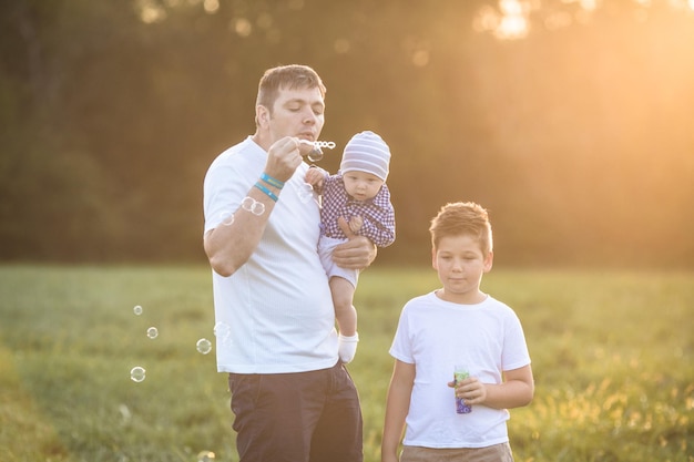 Photo happy family in the field they are having fun playing and blowing bubbles