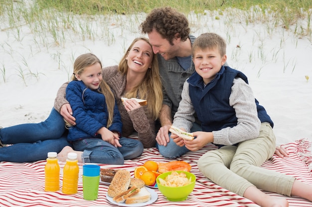 Happy family of four at a beach picnic