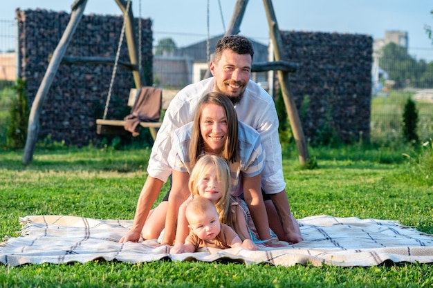 Happy family of four on a blanket in the grass at summer