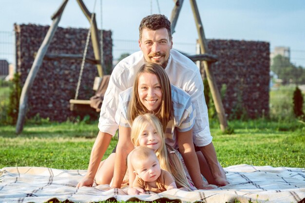 Happy family of four on a blanket in the grass at summer