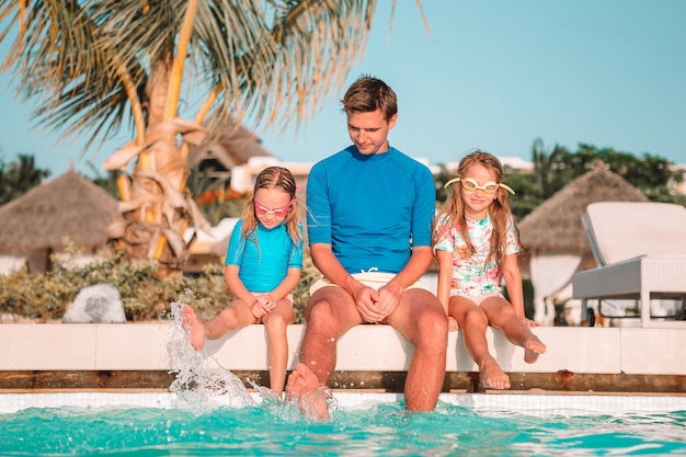 Happy family of four in outdoors swimming pool