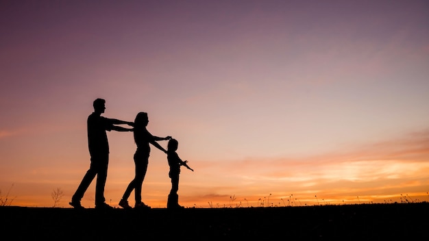 Happy family of four people, mother, father and daughter in meadow.