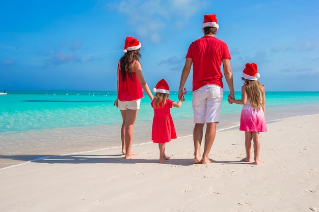 Happy family of four in santa hat on summer vacation
