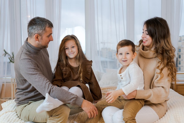 Happy family four spend time on bed hugging and smiling dad mom and little