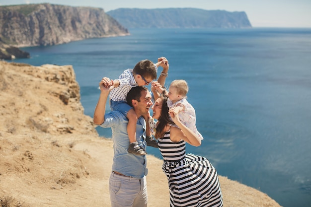 Happy family of four walking in the mountains. Kiss.