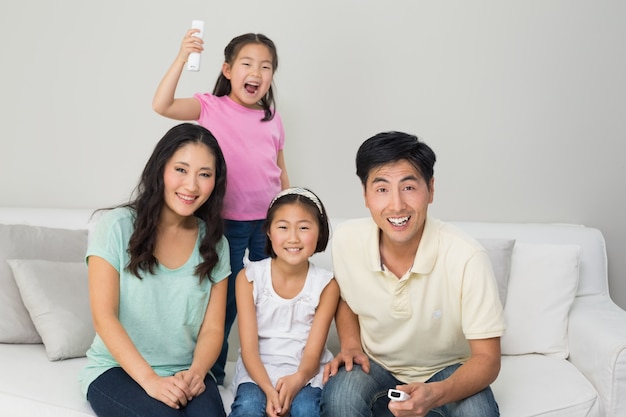 Happy family of four watching tv in living room