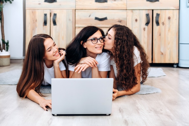 Happy family in front of laptop, daughter kisses her mother