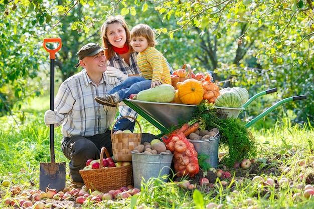 Happy family in the garden with a crop of vegetables and fruit