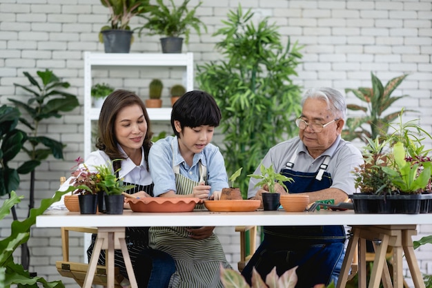 Happy family gardening together in the garden, grandfather grandson and woman taking care of nature