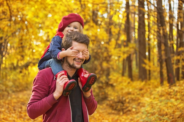 Happy family The girl closes her dads eyes with her hands on autumn walk