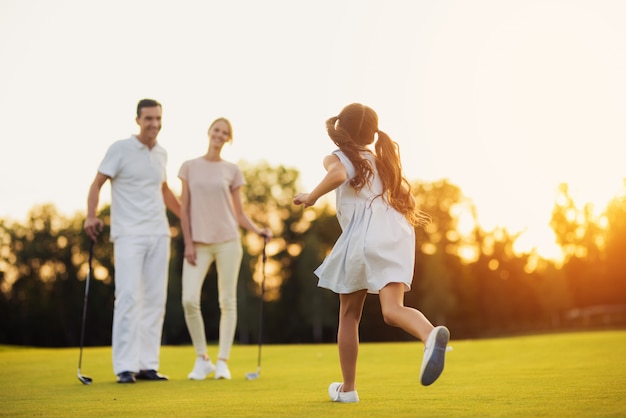 Famiglia felice di giocatori di golf su un prato verde.