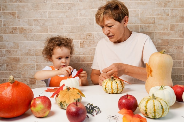 写真 家でハロウィーンのカボチャを作る祖母と幸せな家族の孫娘