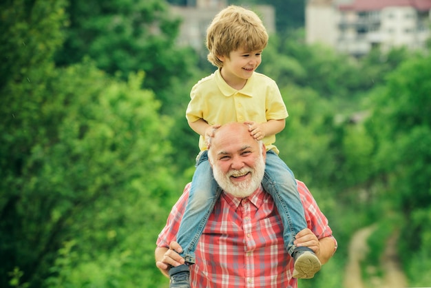 Счастливый семейный дедушка и ребенок на лугу летом на природе Счастливый радостный дедушка весело подбрасывает в воздух концепцию семьи внука