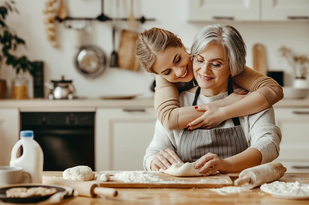 Happy family grandmother old mother motherinlaw and daughterinlaw daughter cook in kitchen knead dough and bake cookies