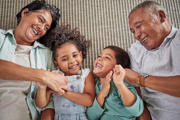 Happy family grandparents and children on a sofa relax and laughing while bonding in e living room together Love laugh and happy kids playing enjoy time and fun game with elderly man and woman