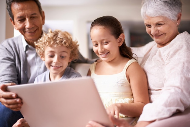 Photo happy family grandparents and children with laptop for communication entertainment or research on sofa at home grandma grandpa and kids smile on computer for online search or networking at house