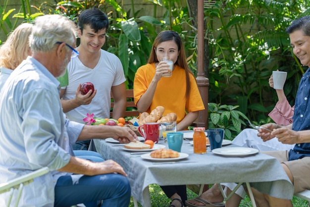 Happy family have fun eating breakfast together at home garden in the morning