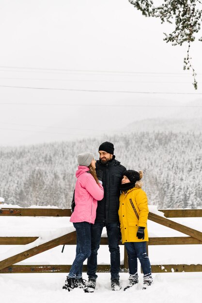 Happy family have fun in winter forest and looking at camera. Mother, father and son playing with snow. Family Christmas concept. Enjoying spending time together