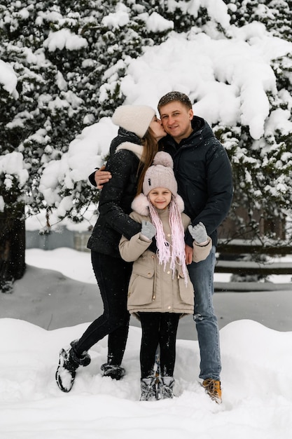 Happy family have fun in winter forest. Mother, father and dauther playing with snow. Enjoying spending time together. Family concept