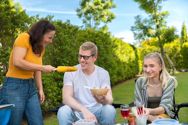 Happy family having barbecue bbq party with red wine in outdoor backyard garden of house with happy