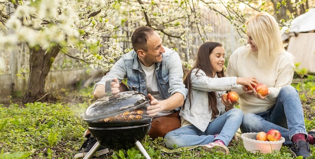 Happy family having barbecue with modern grill outdoors.