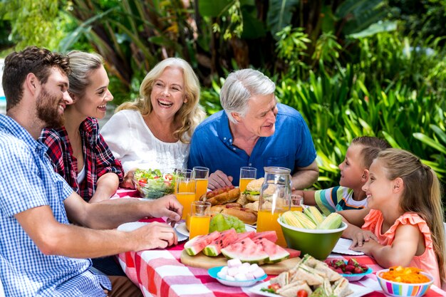 Famiglia felice che mangia alimento alla tavola nell'iarda