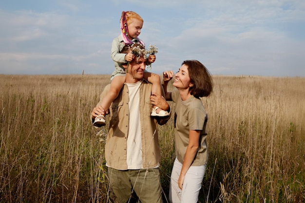 Happy family having fun in autumn or summer day outdoors daughter is sitting on dad