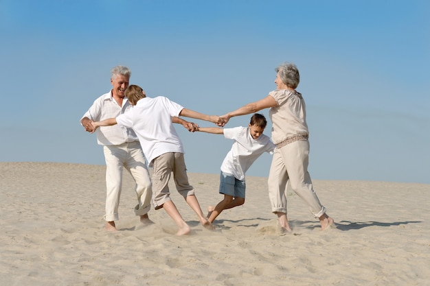 Happy family having fun barefoot in the sand in the summer