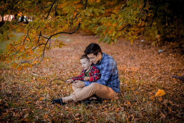 Happy family having fun outdoor in autumn park. Father and son against yellow blurred leaves background. Happy family concept, Father's Day.