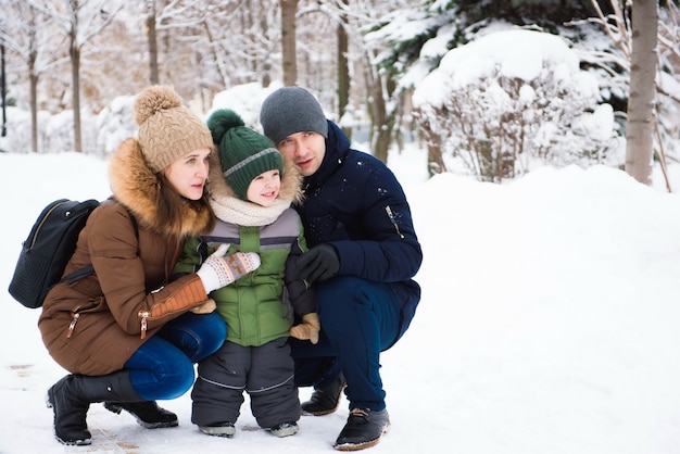 Famiglia felice divertendosi e giocando con la neve nella foresta