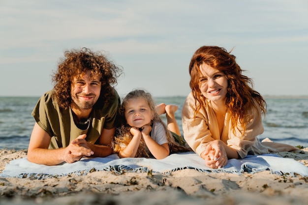 Photo happy family having fun relax and lying on a blanket on sunny beach