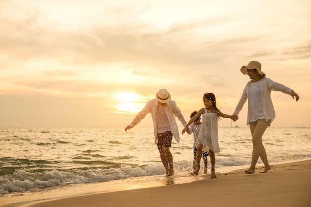 Happy family having fun running on a sandy beach at sunset time