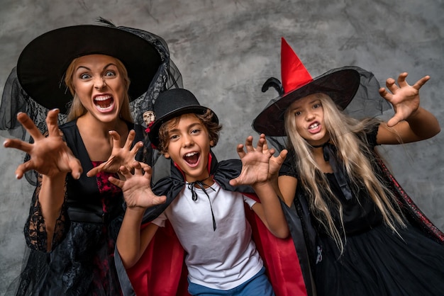 Happy family having fun and scarying with look in camera standing over grey background