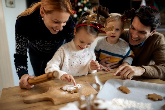 Famiglia felice che si diverte mentre prepara i biscotti di pan di zenzero per natale