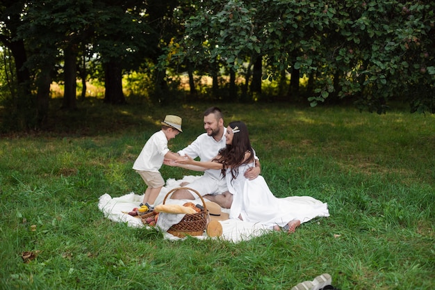 Famiglia felice che fa un picnic all'aperto con il loro figlio carino