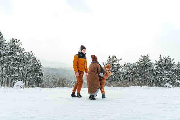 雪の森で冬の屋外散歩をしている幸せな家族