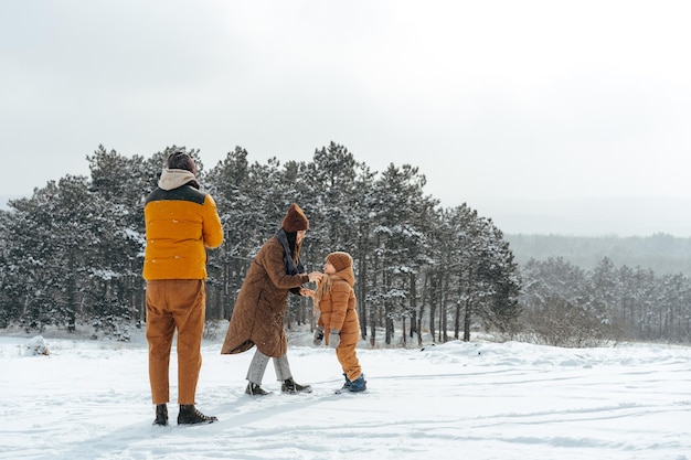 雪の中で屋外で冬の散歩をしている幸せな家族