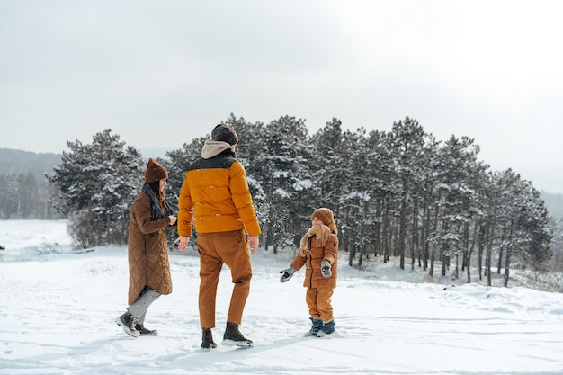 雪の中で屋外で冬の散歩をしている幸せな家族