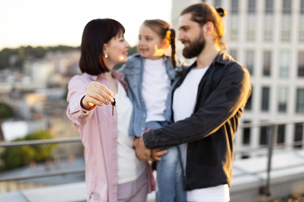 Happy family holding keys to their new home on rooftop