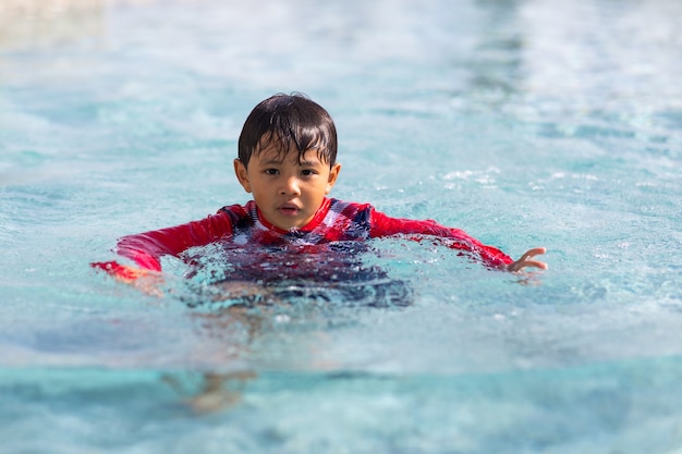 행복한 가족 휴가 시간. 수영장에서 수영을 하는 재미있는 아시아 소년.