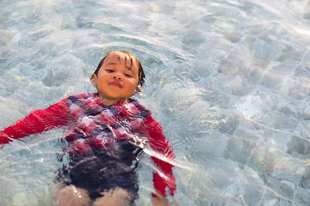 행복한 가족 휴가 시간. 수영장에서 수영을 하는 재미있는 아시아 소년.