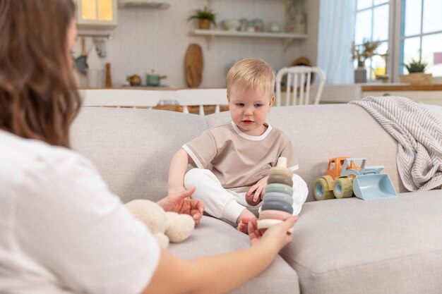 Happy family at home mother and baby boy playing with toys in couch at home indoors little toddler c