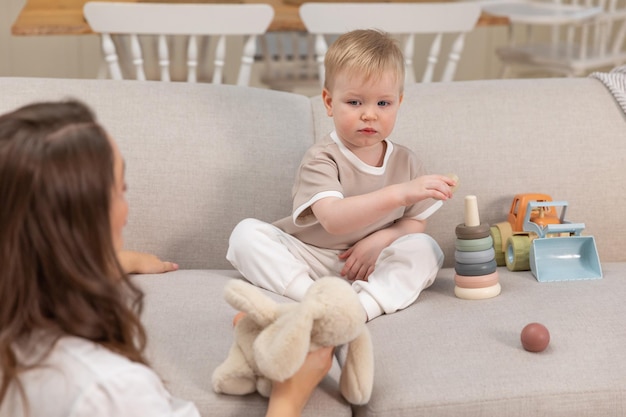 Happy family at home mother and baby boy playing with toys in couch at home indoors little toddler